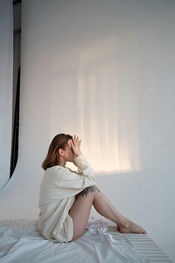 休んでいる女性、 マットレス、 感動的な顔、 平穏な瞬間、 若い女性、 屋内に座っています、 柔らかい照明、 屋内シーン、 リラックスした姿勢、 カジュアルな服装、 自然光