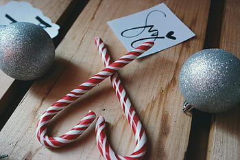 candy canes, silver Christmas balls, wooden surface, holiday spirit, heart shape, close-up, Christmas decorations, festive, holiday, ornaments, candy cane heart