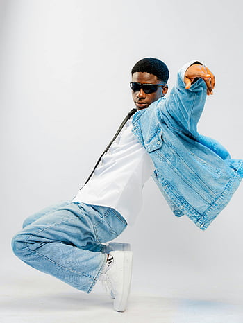 afrikansk mand, denim outfit, moderigtig sort mand, denimjakke, solbriller, Dynamisk positur, Studioindstilling, afslappet mode, gadestil, hvide sneakers, studiofotografering