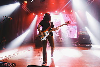 elektrisk gitar, sceneprestasjon, rockekonsert, levende scenelys, bassist, energisk musikk, live performance, konsert scenen, Musikalsk artist, scene søkelys, musikkbegivenhet