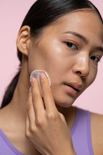 woman, purple tank top, applying facial tonic, skincare, healthy skin, glowing skin, close-up, young woman, facial care, beauty routine, skincare routine