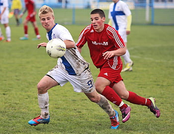 fotbalový zápas, Dospívající fotbaloví hráči, Muddy Grass Field, ostře konkurenční, fotbalový míč, sportovní akce, venkovní sporty, Mládežník fotbal, Atletická soutěž, Fotbalové uniformy, travnaté hřiště