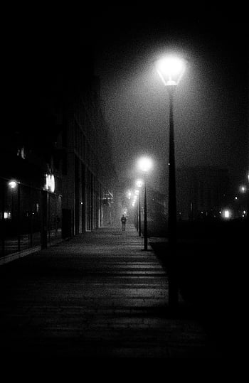 foto em tons de cinza, pessoa caminhando, calçada, luzes da rua, Preto e branco, mal iluminado, rua nebulosa, cena misteriosa, cena noturna, rua urbana, fotografia de rua
