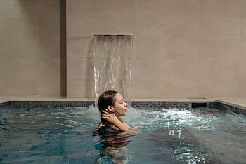 woman bathing, indoor swimming pool, cascading waterfall, adult woman, relaxing, spa, water feature, indoor pool, spa relaxation, spa treatment, spa experience
