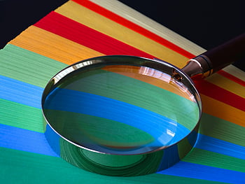 brown handle magnifying glass, vibrant rainbow-colored paper, close-up, magnifying glass, rainbow colors, close up, magnification, colorful background, detailed view, optical tool, paper texture