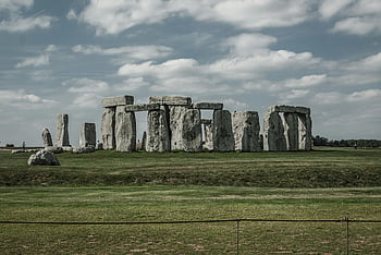 Stonehenge, London, England, iconic monument, dramatic sky, lush green grass, ancient stones, historical site, outdoor landmark, prehistoric structure, tourist attraction