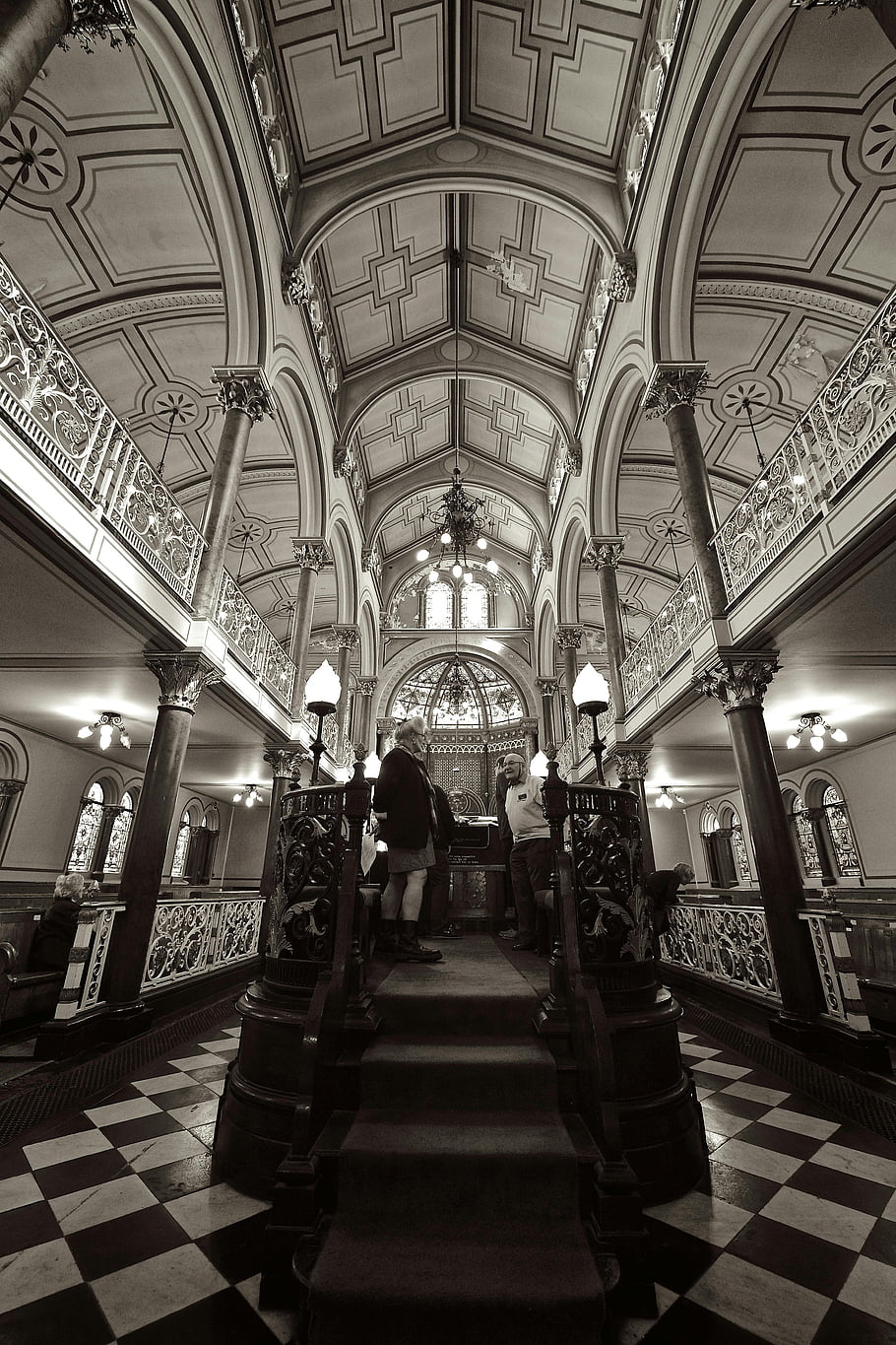 historic synagogue, Brighton UK, ornate architecture, religious heritage, interior design, checkered floor, stained glass windows, arched ceilings, chandeliers, decorative columns, black and white photography