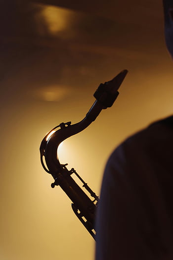 silueta saxofonu, saxofonista, teplé podsvícení, jazzová atmosféra, hudební nástroj, silueta fotografie, jazzová hudba, saxofon detail, hudební výkon, detail saxofonu