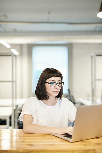 woman using laptop, focused young woman, glasses, modern open office, working on laptop, open office environment, professional setting, businesswoman, office worker, desk work, concentration