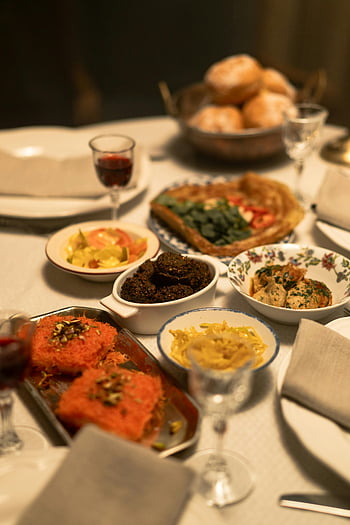 cooked food, dinner table, traditional dishes, festive celebrations, wine glasses, beautifully set, celebratory meal, table setting, gourmet dishes, holiday feast, dining table