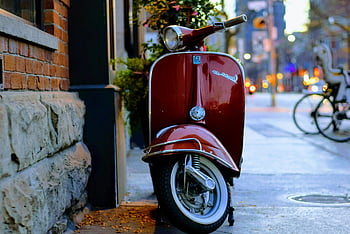 red Piaggio Vespa, motor scooter, parked, gray and red concrete building, brick wall, urban street, classic Vespa, red Vespa, scooter, urban setting, brick building