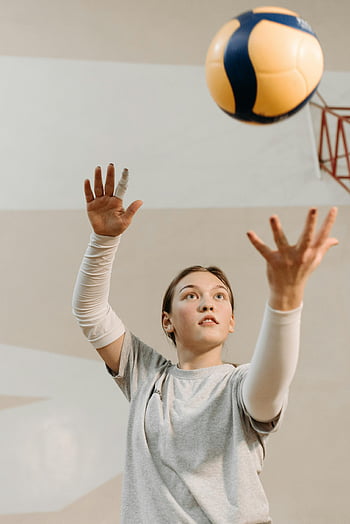 woman in gray shirt, playing volleyball, indoor practice, female athlete, reaching for ball, volleyball game, sports action, indoor sports, volleyball player, determined athlete, volleyball practice