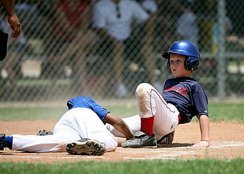 Baseballspieler, selektiver Fokus, intensives Spiel, sonnenbeschichtetes Feld, junge Spieler, Action-Schuss, Sportfotografie, Baseballaktion, Feldaktion, Spielmoment, Outdoor-Sportarten