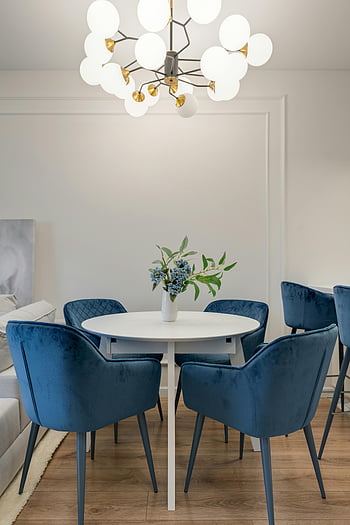 fiori sul tavolo, sedie di velluto blu, tavola rotonda, lampadario elegante, Elegante sala da pranzo, arredamento della sala da pranzo, Setup da pranzo moderno, spazio da pranzo interno, Home Interior Design, illuminazione del lampadario, centrotavola floreale