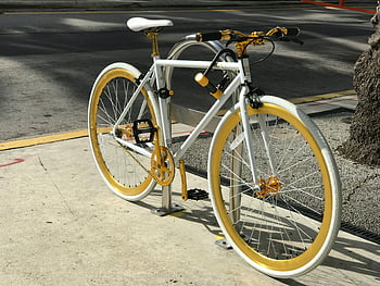 bicycle wheel, white bicycle, gold bicycle, urban transportation, sunlit street, sleek bicycle, city bike, bicycle parking, street bike, modern bicycle, bike design