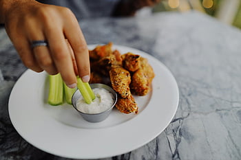 celery, ranch dip, crispy chicken wings, close-up, hand dipping, celery stick, ranch sauce, plate, food photography, appetizer, snack