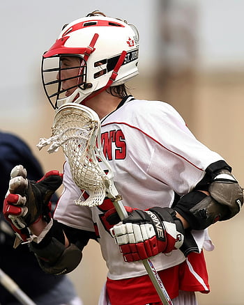 lacrosse player, white and red uniform, focused game, helmet, lacrosse stick, sports action, male athlete, team uniform, competitive sport, outdoor game, protective gear