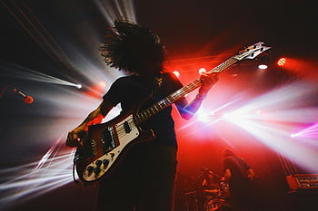 live rockekonsert, Bassist i aksjon, levende scenelys, intens konsert, sceneprestasjon, rockmusiker, konsertfotografering, levende musikk, scene belysning, rockeband, bassgitar