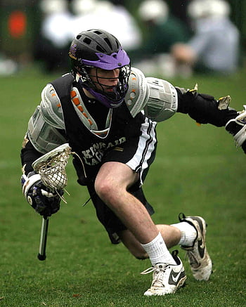 lacrosse player, black sports jersey, mid-action, sports game, dynamic shot, lacrosse stick, protective gear, outdoor sports, athletic action, field sports, competition intensity