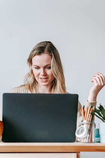 fokussierter Freiberufler, Arbeiten am Laptop, Innenministerium, natürliches Licht, gemütliche Einstellung, Frau arbeitet, Laptop-Arbeit, Heimarbeitsplatz, professionelle Einstellung, Heimarbeit, Innenbüro