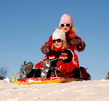 girls playing on snow, sled ride, snowy hill, sunny winter day, children enjoying, winter fun, outdoor activities, winter sports, kids sledding, snow play, winter recreation