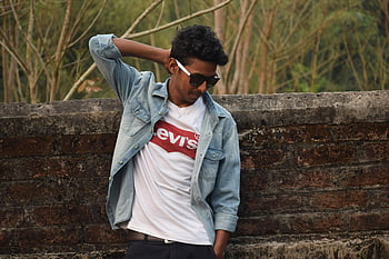 Mand i denimjakke, ung mand poserer, denimjakke, solbriller, stil og selvtillid, Levi's t-shirt, udendørs fotografering, afslappet mode, murmur baggrund, selvsikker positur, gadestil