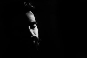 black and white portrait, man with black beard, thoughtful expression, deep shadows, captivating, monochrome, high contrast, facial features, side profile, artistic photography, dramatic lighting