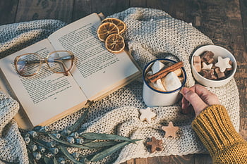 Marshmallows in Mug, hot chocolate, open book, autumn elements, dried oranges, cinnamon sticks, cozy flat lay, knitted blanket, star-shaped marshmallows, wooden table, glasses