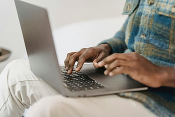 afrikansk amerikansk mand, afslappet tøj, bruger bærbar computer, maskinskrivning, siddende indendørs, arbejder fjernt, ung mand, bærbar, fjernbetjening, indendørs indstilling