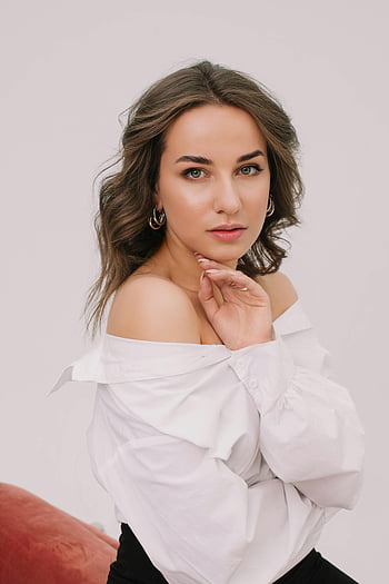 vrouwenportret, wit overhemd, bruin haar, elegant, zelfverzekerde pose, binnenshuis, modefotografie, off-shoulder top, vrouwelijk model, studio opname