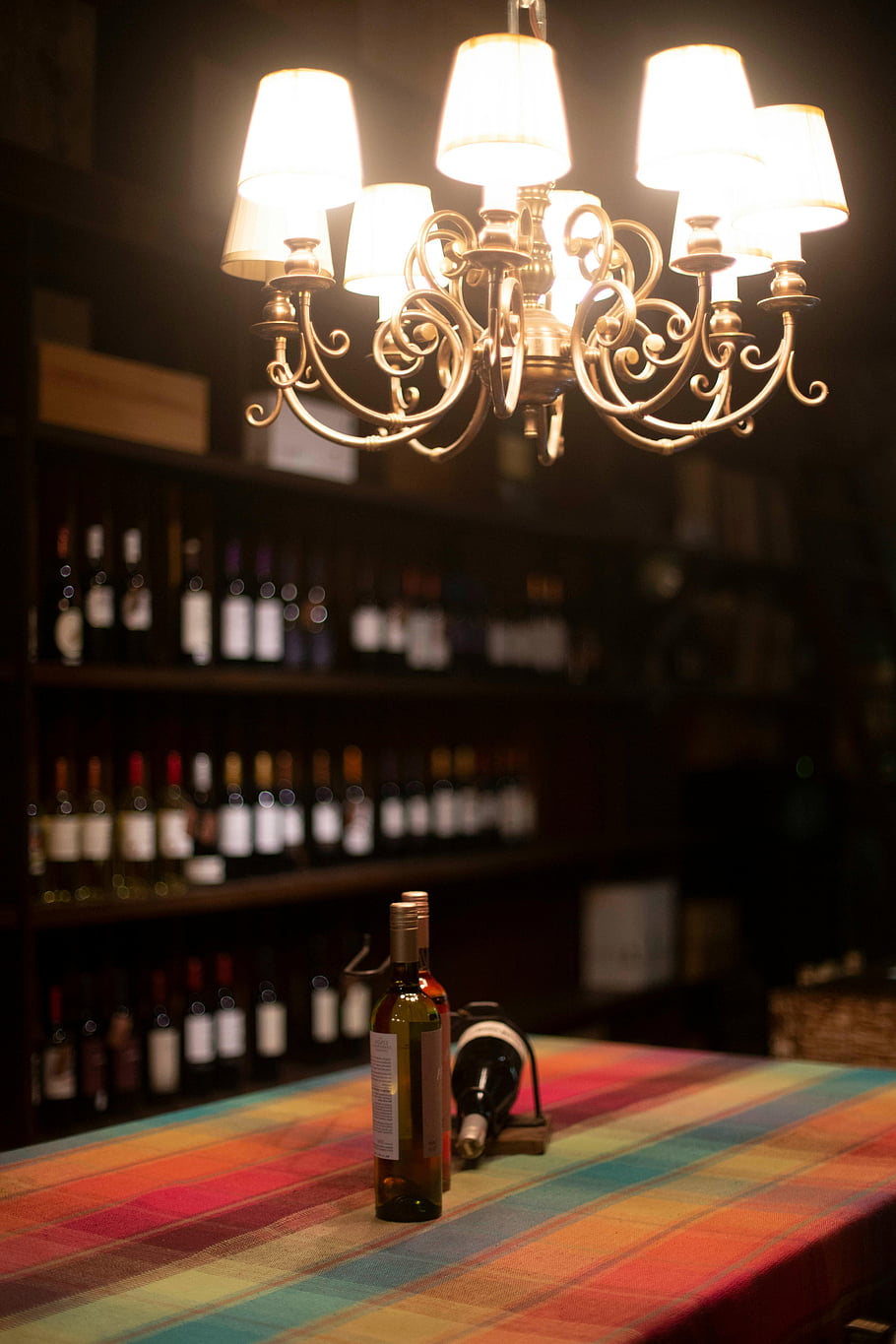 wine bottles, chandelier, interior design, soft lighting, vintage chandelier, colorful display, table setting, wine collection, ambient lighting, wine cellar, decorative lighting