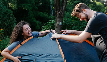 felice giovane coppia, Campeggio forestale, Impostazione della tenda, Sunny Camping Trip, avventura all'aria aperta, attività naturali, divertimento in campeggio, impostazione della foresta, Coppia che si gode il campeggio, ricreazione all'aperto, configurazione della tenda