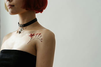 red hair, black tube top, red floral tattoo, minimalist indoor setting, woman's shoulder, artistic tattoo, red tattoo, minimalist photography, indoor portrait, shoulder tattoo, red and black