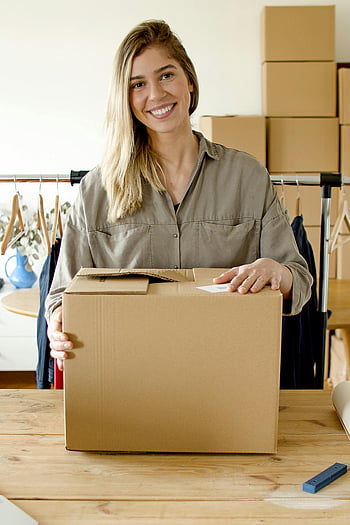 woman smiling, holding package, online store, small business, indoor packaging, cardboard box, business owner, e-commerce, product packaging, home office, delivery preparation