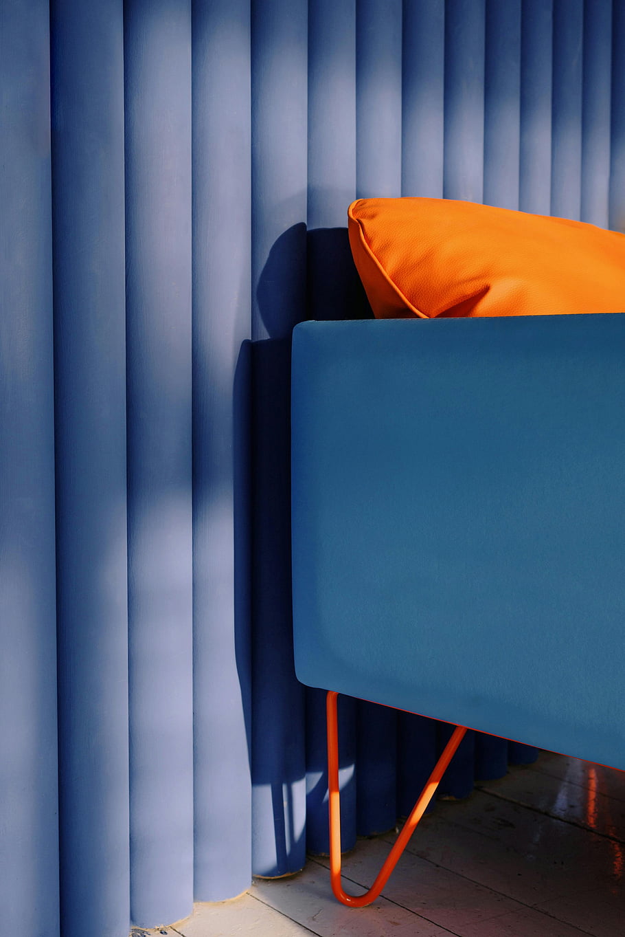 orange pillow, blue sofa, vibrant orange, stylish blue, vertical blue curtain, interior design, modern furniture, living room decor, color contrast, home decor, contemporary style
