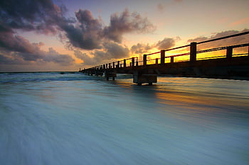 wooden pier, ocean waves, sunset, vivid skies, tranquil scene, pier into ocean, sunset photography, ocean photography, beach sunset, long exposure, serene landscape