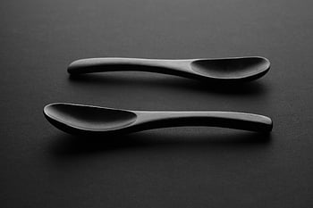 Twee lepels, houten lepels, monochrome afbeelding, donker oppervlak, minimalistisch ontwerp, artistieke foto, zwart en wit, eenvoudige samenstelling, keukengerei, moderne esthetiek, donkere achtergrond