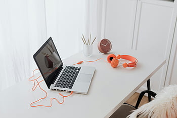 bärbar dator, orange hörlurar, vitt skrivbord, minimalistisk arbetsyta, ren skrivbord, arbetsytans inställning, skrivbordstillbehör, kontorsskrivbord, arbeta hemifrån, skrivbordsorganisation, teknisk arbetsyta