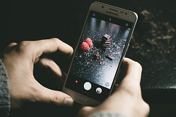 γκρι smartphone της Samsung, σοκολάτες, σμέουρα, γκρο πλαν, σκοτεινή επιφάνεια, φωτογράφηση smartphone, φωτογραφία τροφίμων, samsung τηλέφωνο, κομμάτια σοκολάτας, σκούρο φόντο