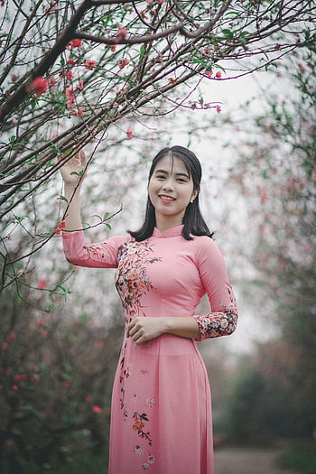 Ροζ Ao Dai, floral φόρεμα, χαμογελαστή γυναίκα, πάρκο γεμάτο λουλούδια, γαλήνια σκηνή, ζωντανή σκηνή, ροζ φόρεμα, μαύρος λουλουδιός, παραδοσιακό φόρεμα, εξωτερικό πορτρέτο, μόδα της άνοιξης