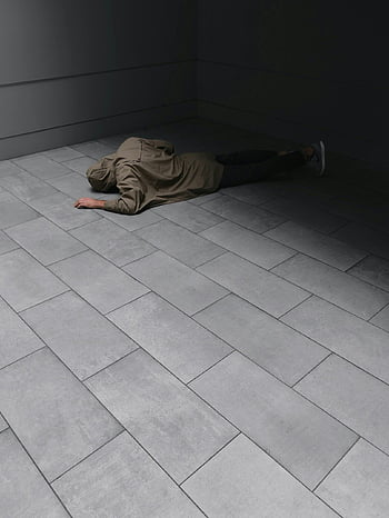 szürke kapucnis, fekete farmer, feküdt a padlón, Modern szürke csempézett padló, minimalista városi környezet, feküdt ember, beltéri jelenet, kortárs design, városi környezet, csempézett padló, minimalista stílus
