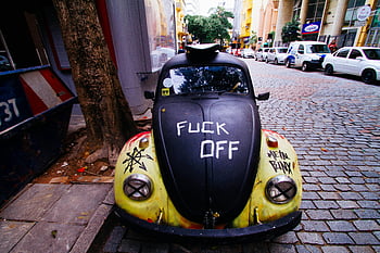 Black Volkswagen Beetle, graffiti, city street, cobblestones, classic car, urban scene, parked car, street art, vintage car, outdoor setting, public display