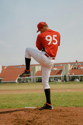 baseball spiller, rød jerseyskjorte, hvide bukser, forbereder sig på at pitche, baseball bane, skyfri himmel, sport uniform, udendørs sport, baseball kamp, kande, atletisk gear