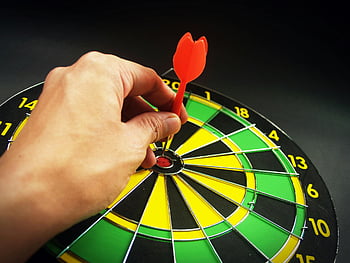 person, holding, red dart, green yellow black dart board, dart, board, target, game, sports, recreation, accuracy