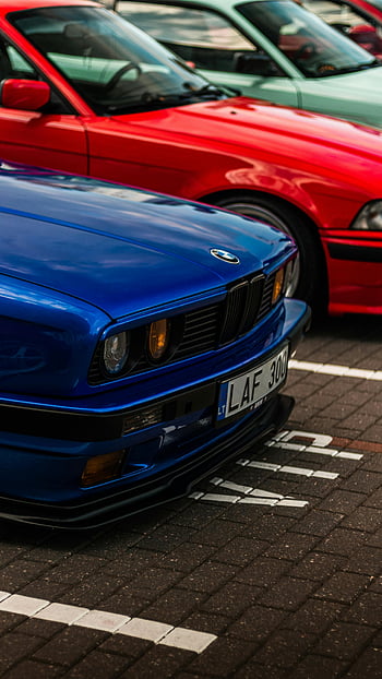 Blue BMW E30, Red BMW E36, classic BMW cars, parking lot, Lithuania, outdoor parking, colorful lineup, vintage cars, classic cars, car enthusiasts, automotive photography