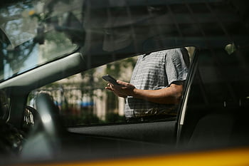 man using smartphone, taxi car, urban setting, inside car, visible through window, smartphone user, city scene, passenger in taxi, urban transportation, mobile device, car interior