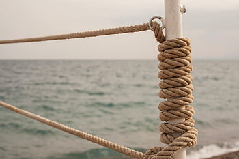 rope knot, nautical themes, ocean background, close-up photo, detailed view, rope on post, maritime scene, nautical rope, rope detail, seaside image, nautical knot