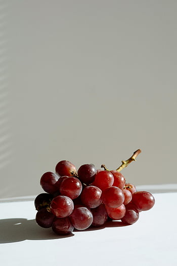 hrozny, červené hrozny, bílý stůl, minimalistické nastavení, přirozené světlo, ovocné fotografie, stálý život, fotografování potravin, detail, jednoduché pozadí, čerstvé hrozny