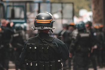 poliziotto, casco, attrezzatura antisommossa, Mantenere l'ordine, pattuglia diurna, ufficiali in azione, sfondo sfocato, marcia completa, forze dell'ordine, sicurezza pubblica, controllo della folla