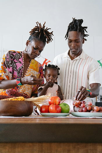 Oslava Kwanzaa, rodinné lepení, vnitřní kuchyně, ovoce, radostné okamžiky, afroamerické rodiny, kulturní tradice, Slavnostní shromáždění, jednotnost, Oslava svátků, Zdravé stravování